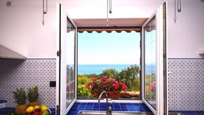 Una cocina con vista al mar, un lavabo y un bol de fruta.