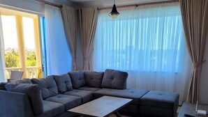 A modern living room with a sectional sofa, a wooden coffee table, and a small table.
