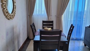 A dining area with a table and chairs, a decorative mirror, and a view through the window.