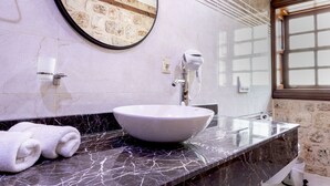 A bathroom with a large round mirror, a white sink, and a marble countertop. -  WOO Town  (Antalya)