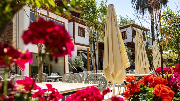 An outdoor seating area with tables and chairs, surrounded by flowers and umbrellas. -  WOO Town  (Antalya)