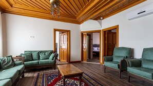 A spacious living room with wooden flooring, a green sofa set, a wooden coffee table, and a patterned rug. -  WOO Town  (Antalya)