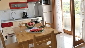 Cocina compacta con comedor, microondas, cafetera y vistas al exterior.