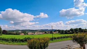 Un paysage rural avec une route, des champs verdoyants et des maisons dispersées.