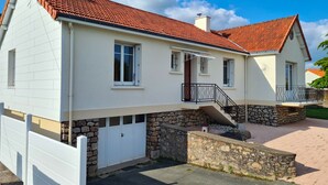 Une maison à deux étages, avec un toit recouvert de tuiles rouges, des murs extérieurs blancs et des fondations en pierre.