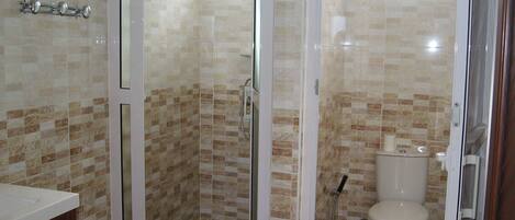 Une salle de bain avec une douche à parois de verre, des toilettes et un lavabo.
