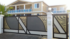 A gated entrance with a zebra-striped design, a nameplate reading "Villa Paprika," and a balcony with a white railing. - COTOMILI ACCOMMODATION WITH SWIMMING POOL (Trou aux Biches)