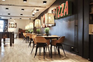 A restaurant interior with wooden tables, chairs, and a wall sign reading 'PIZZA'. - Hotelli Jämsä (Jamsa)