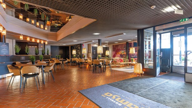 Un interior moderno con una zona de estar central, una recepción y un ventanal grande.