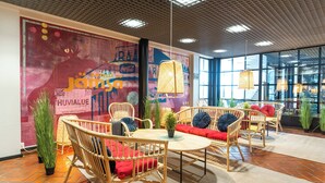 Un interior moderno con muebles de mimbre, una mesa central y un gran mural en la pared.