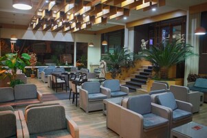 A spacious lobby with comfortable seating, a staircase, and decorative plants.