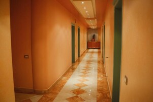 A long, narrow hallway with a patterned floor and orange walls.