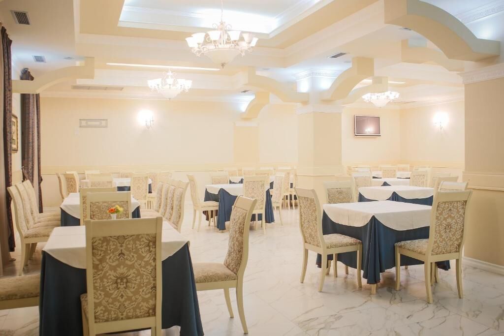 Un salón de banquetes con mesas redondas y sillas, candelabros y un diseño arquitectónico clásico.
