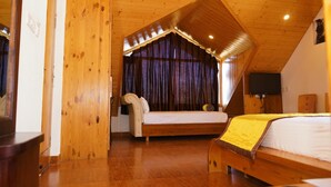 Une chambre avec un plafond en bois, un lit recouvert d’une couverture jaune, un canapé et un téléviseur.