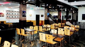 Un restaurant doté de nombreuses tables et chaises, d’un escalier et de diverses décorations murales.