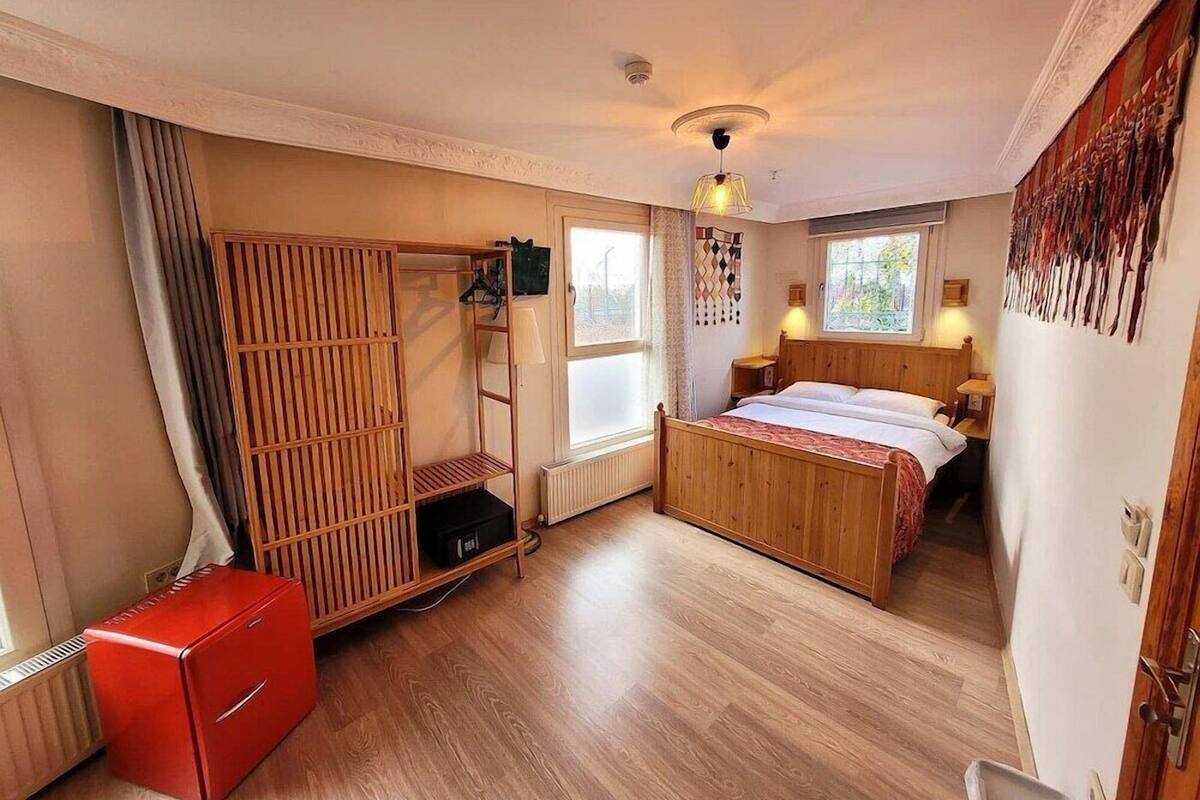 A bedroom with a bed, a wardrobe, a radiator, a window, and a red cabinet.