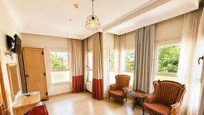 Une pièce spacieuse avec un plancher en bois, un réfrigérateur rouge, un meuble en bois, une chaise, un canapé et une table.