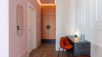 A modern interior with a wooden floor, a seating area with a table and chairs, and a mirror on the wall.