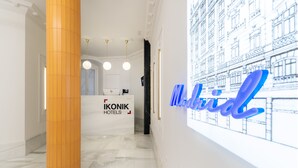 A reception area with a reception desk labeled "IKONIK HOTELS" and a large blue sign with the word "Madrid". - Ikonik Gran Via (Madrid)