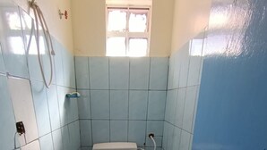 A small bathroom with a toilet, a window, and a blue door.