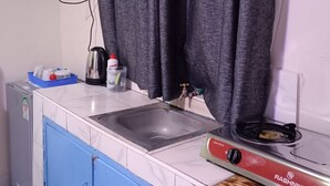 A compact kitchen with a sink, a stove, and a blue cabinet.