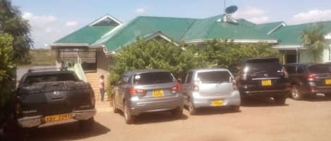 A parking lot with several cars parked in front of a building with a green roof and satellite dish.