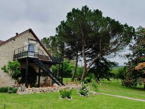 Ein Steinhaus mit Balkon und einer Treppe, die zu einer zweiten Etage führt.
