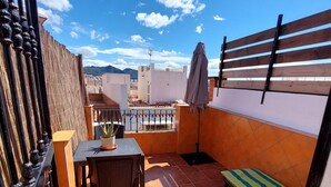 A rooftop terrace with a table, chairs, a bench, a bamboo fence, and a view of the cityscape. - Holiday Studio 'Lola' with Mountain View, Private Terrace, A/C & Wi-Fi (Nerja)