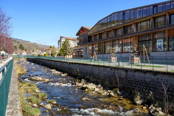 Un río fluye junto a un edificio con balcón y terraza de madera.