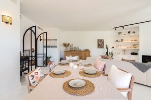 A dining area with a table set for four, surrounded by chairs, a sofa, and a bookshelf.