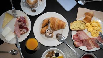 Eixida de matí amb plats de menjar, una tassa de cafè i un telèfon intel·ligent sobre una taula.