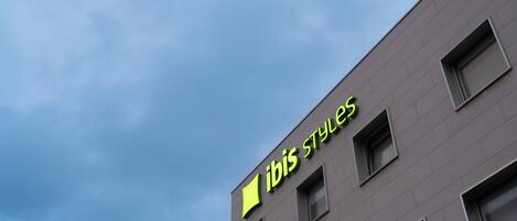 Un edificio con un letrero que dice "ibis Styles" contra un cielo nublado.