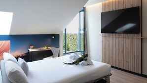 A modern hotel room with a large bed, a desk, and a flat-screen TV mounted on the wall. - Ibis Styles Santander  (Santander)