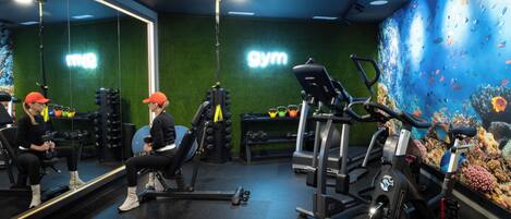 Un gimnasio con equipo de ejercicio, un espejo grande y un mural subacuático en la pared.