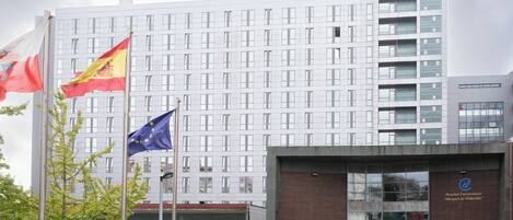 A modern building with a large glass entrance, flags, and bicycles.