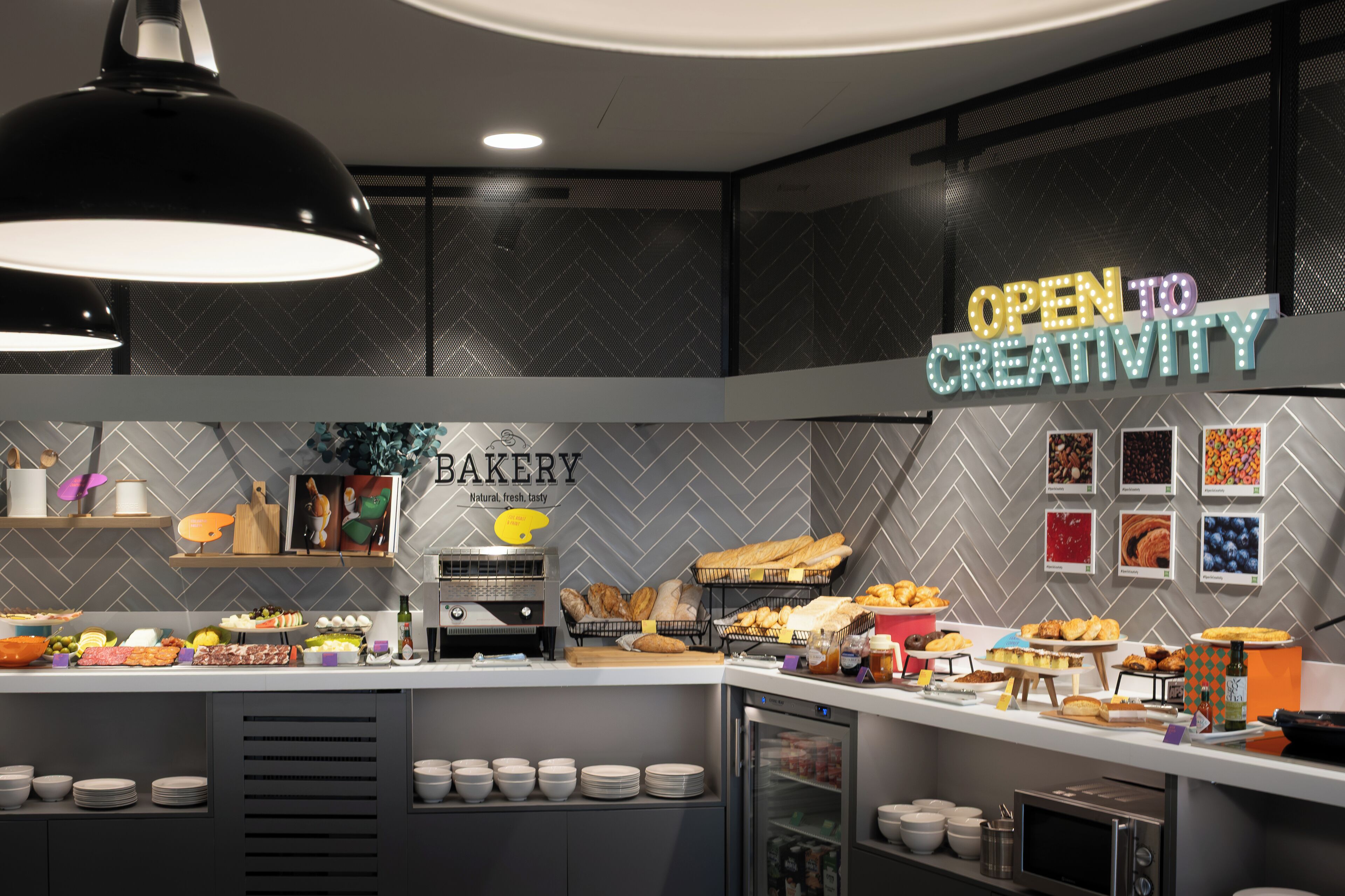 A bakery counter with various baked goods and a sign that reads 'OPEN TO CREATIVITY'.