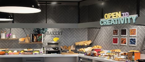 A bakery counter with various baked goods and a sign that reads 'OPEN TO CREATIVITY'.