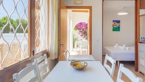 Una habitación con una mesa de comedor, sillas, una cama y un ventanal con un panel decorativo.
