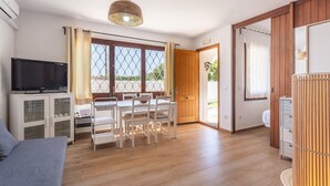 Una habitación con televisión, una mesa de comedor con sillas, un sofá y un armario de madera.