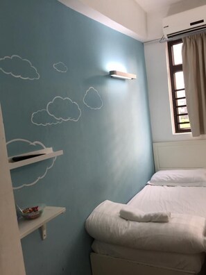 A bedroom with a bed, a window with curtains, a wall with cloud decals, and a shelf with a basket. - Starfish Hostel (Kowloon)