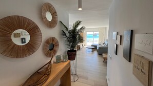Una sala moderna con un espejo grande, una planta en maceta y un banco de madera.