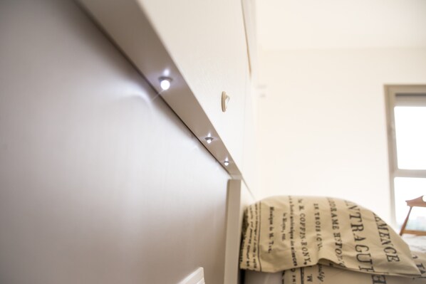 A white wall with a window, a door, and a partially visible text on a hanging item.