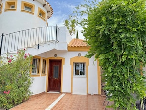 A two-story building with a balcony, a wooden door, and a tiled entrance.