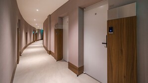 A modern hotel corridor with a curved ceiling, wooden doors, and a light-colored floor. - Brown Dot Hotel Eurwangri (Incheon)