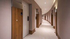 A modern hotel hallway with wooden doors, numbered 505, and a curved ceiling design. - Brown Dot Hotel Eurwangri (Incheon)