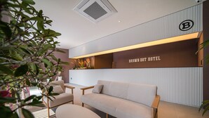A modern hotel lobby with a sofa, chairs, and a reception desk. - Brown Dot Hotel Eurwangri (Incheon)