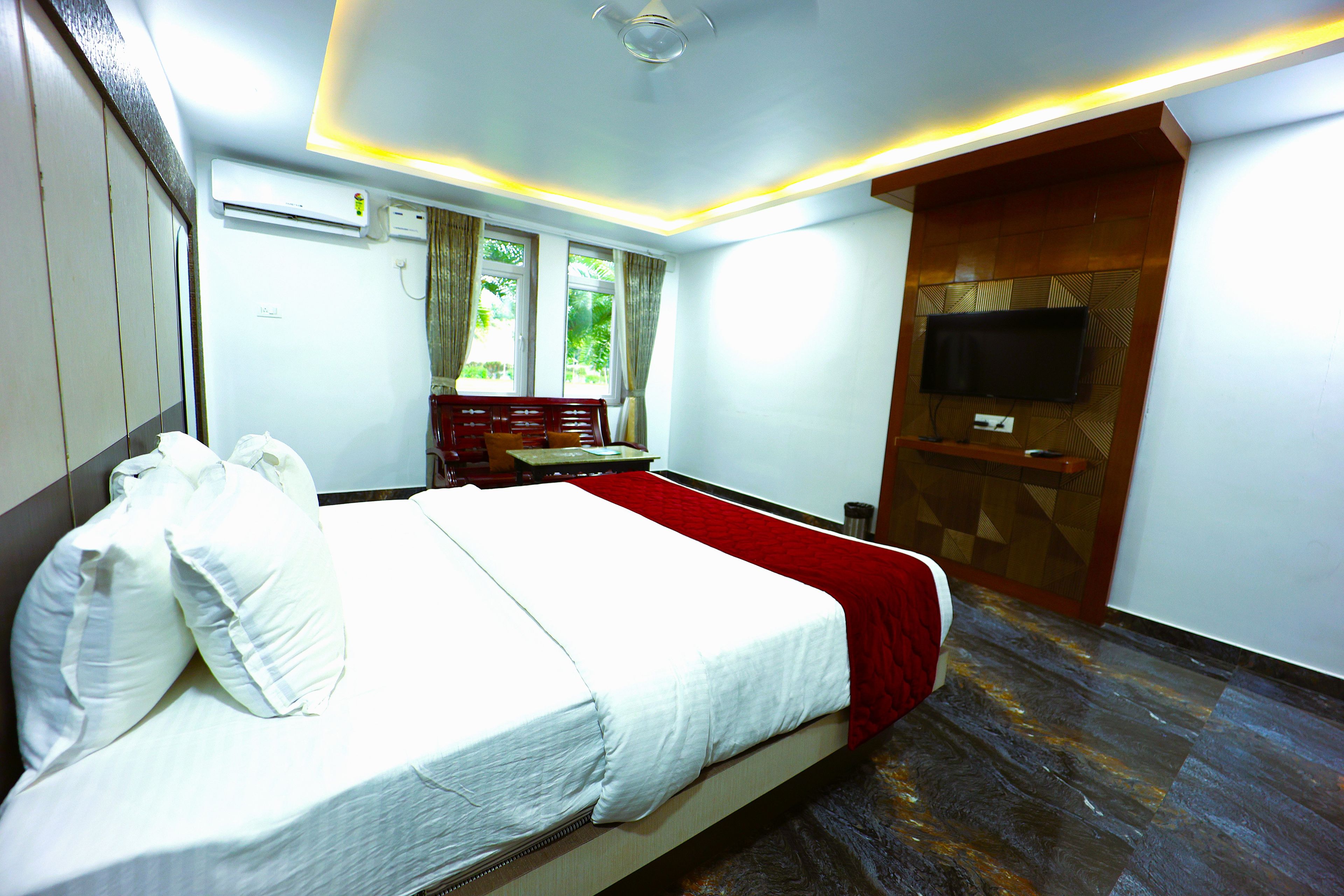 A hotel room with a bed, a desk, a TV, and a window with curtains.