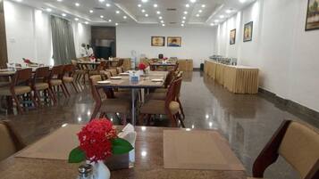 A conference room with multiple tables and chairs, a water dispenser, and a buffet area.