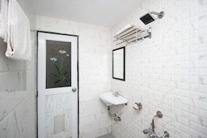 A bathroom with a white tiled wall, a sink, a mirror, and a towel hanging on the wall.