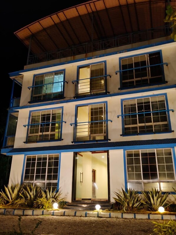 A multi-story building with a flat roof, multiple windows with blue frames, and a central entrance. - Sea Breeze Beach Resort (Murud)